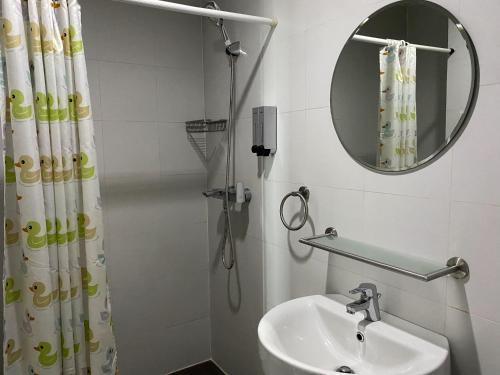 a bathroom with a sink and a mirror and a shower at KL Tower Makati Apartments by PH Staycation in Manila