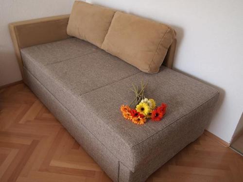 a brown couch with a bouquet of flowers on it at Apartments Mira in Tučepi