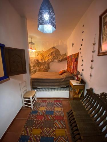 Habitación con cama y pintura en la pared en Casa La Maquica, en Campo de Criptana