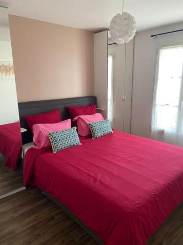 um quarto com uma grande cama vermelha e 2 almofadas em Jessi home em Limeil-Brévannes