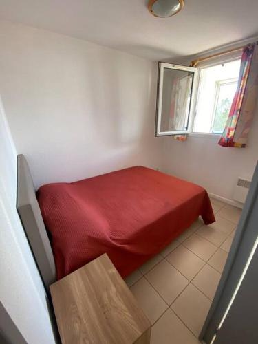 - une petite chambre avec un lit rouge et une fenêtre dans l'établissement T2 agréable proche de la mer (mar vivo-sablettes), à La Seyne-sur-Mer