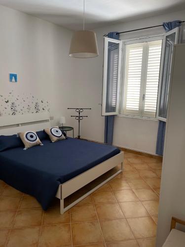 una camera con un letto blu e due finestre di Casa Vacanza Sicilia Dolce Mare a Balestrate