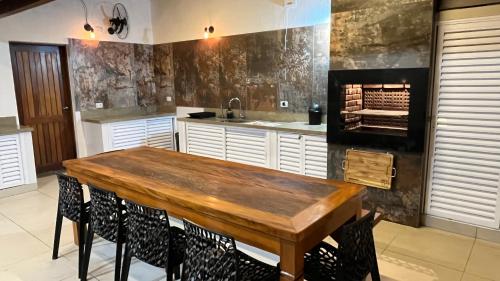 eine Küche mit einem Holztisch und einem Kamin in der Unterkunft Casa Pé na Areia com Piscina Climatizada in Bertioga