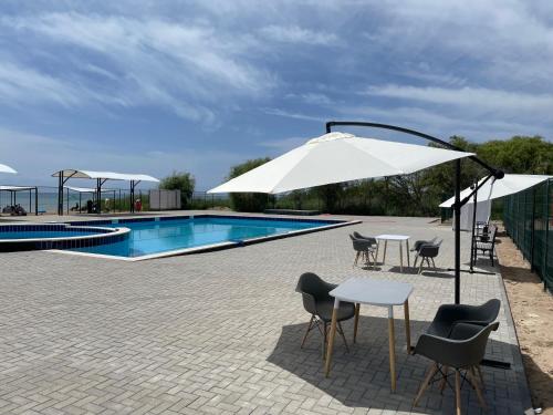 a pool with a table and chairs and an umbrella at Apartment, Центр Отдыха Atlantis, Сары-Ой, 1-й этаж in Chon-Sary-Oy