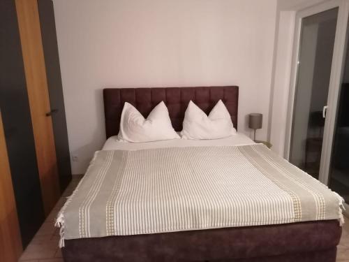 a bed with white pillows and a brown headboard at Appartment Nocksteinblick in Guggenthal