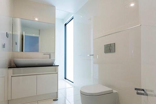 Baño blanco con lavabo y aseo en Large Executive 3 bedroom, en Yarralumla