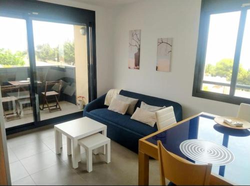 ein Wohnzimmer mit einem blauen Sofa und einem Tisch in der Unterkunft Frente mar, piscina, Delta in Alcanar