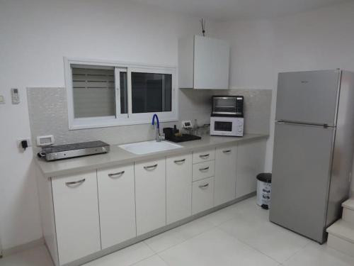 a kitchen with white cabinets and a white refrigerator at המקום ברותם in Nahariyya