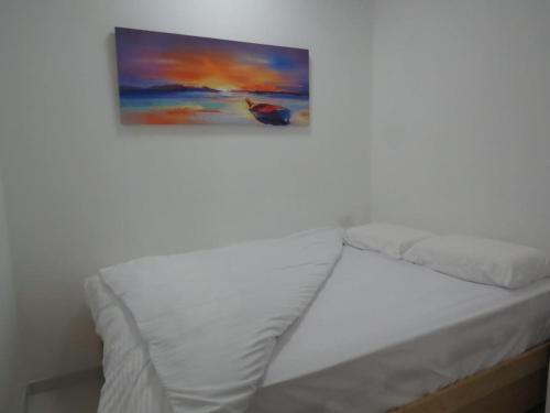 una cama blanca con una pintura en la pared en המקום ברותם en Nahariyya