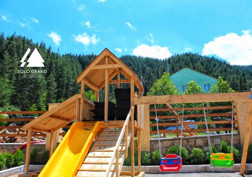 a wooden play structure with a slide and a playground at Solo Grand Boshuri Hotel Wellness Resort 