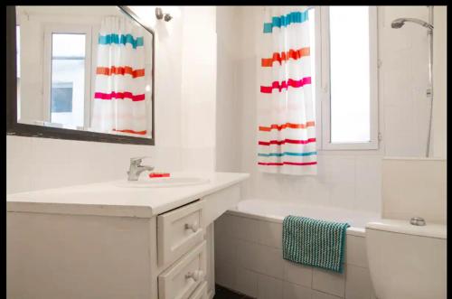 une salle de bain blanche avec un lavabo et un miroir dans l'établissement Appartement proche Montmartre, à Paris