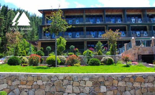 a hotel with a stone wall in front of a building at Solo Grand Boshuri Hotel Wellness Resort in Qvemo Boshuri
