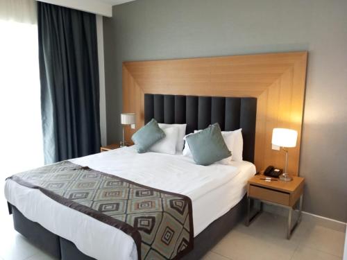 a bedroom with a large bed with a wooden headboard at Lander Luxury Apartment, 5 Star Hotel, Kusadasi in Kuşadası