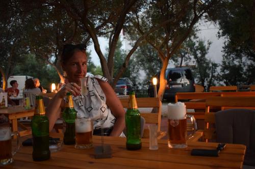 a woman sitting at a table with bottles of beer at Panorama Apartments in Povljana