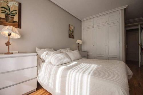 a white bedroom with a white bed and a dresser at Apartamento + parking en el centro de Cartagena in Cartagena