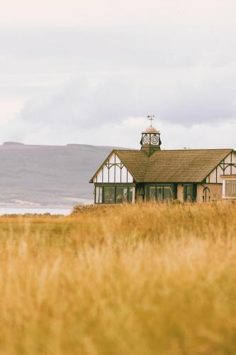 a building with a clock tower on top of a field at Dornoch Station in Dornoch