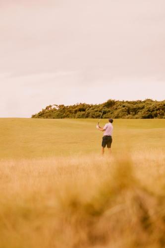 a man holding a baseball bat in a field at Dornoch Station in Dornoch