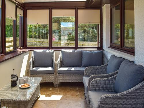 a screened in porch with two couches and a table at Lowesmuir Cottage in Cumnock