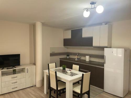 y cocina con mesa, sillas y nevera. en Apartmani Vrla en Vladičin Han