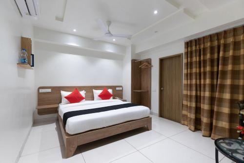 a bedroom with a bed with red pillows at Sapphero Akshar Inn- Jamnagar in Jamnagar