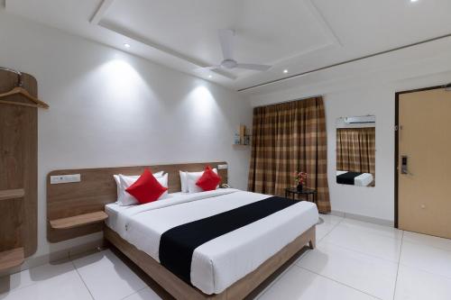 a bedroom with a large bed with red pillows at Sapphero Akshar Inn- Jamnagar in Jamnagar