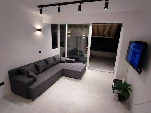 Astramaris Apartments في أوكرونغ دونغي: غرفة معيشة مع أريكة وتلفزيون بشاشة مسطحة