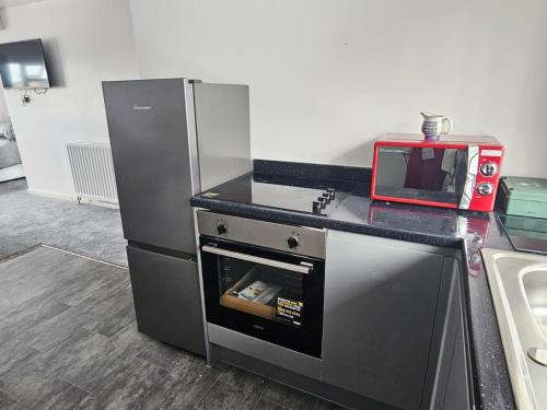 cocina con nevera y microondas rojo en Modern comfortable quiet self contained apartments, en Brackley