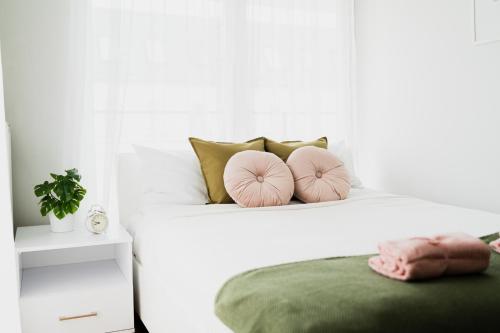 - une chambre blanche avec un lit et des oreillers roses dans l'établissement Apart City Center - 3 Rooms - Parking Place, à Wrocław