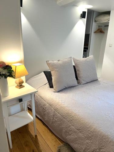 - un lit avec deux oreillers et une table avec une lampe dans l'établissement Le 8, à Honfleur