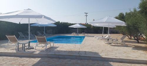 a patio with chairs and umbrellas and a pool at Koukouri Suites in Areopoli