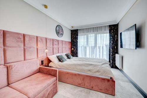 ein Schlafzimmer mit einem großen rosa Bett und einem Sofa in der Unterkunft APARTAMENTY Z TARASEM NA DACHU NA WYDMACH W MIĘDZYWODZIU in Międzywodzie