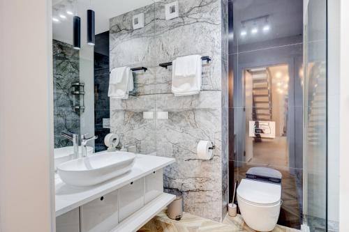 a bathroom with a white toilet and a sink at APARTAMENTY Z TARASEM NA DACHU NA WYDMACH W MIĘDZYWODZIU in Międzywodzie