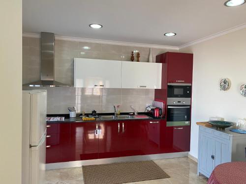uma cozinha com armários vermelhos e electrodomésticos brancos em Chez Ilda - Casa da Ilda Alojamento Local 