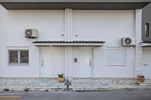 a white house with two white doors and speakers at Garden Apartment in Amarynthos II in Amarinthos
