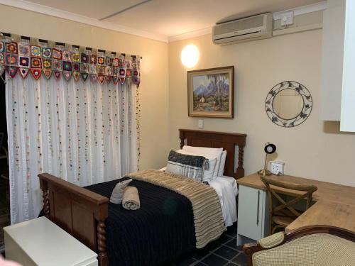 1 dormitorio con cama, mesa y espejo en Skinkikofi Guest House, en Paarl