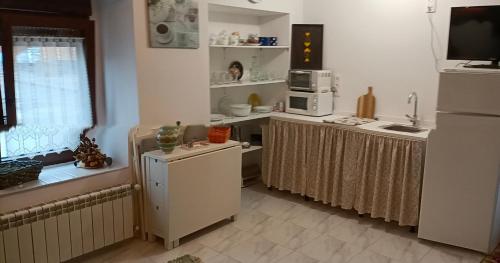 a kitchen with white cabinets and a sink and a microwave at CASA TITA in Campo de Villavidel