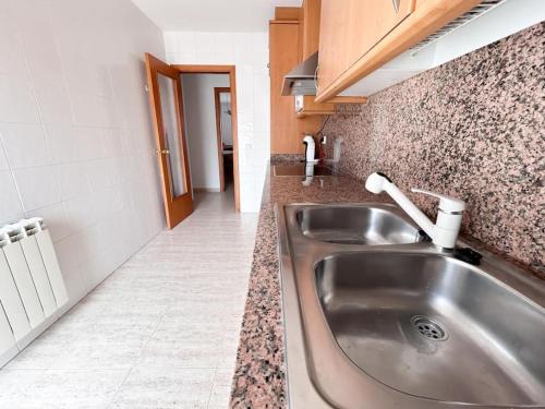 Fantástico y acogedor apartamento en Sant Feliu في سان فيليو دي غيكسولس: مطبخ مع حوض حديد قابل للصدأ في الغرفة