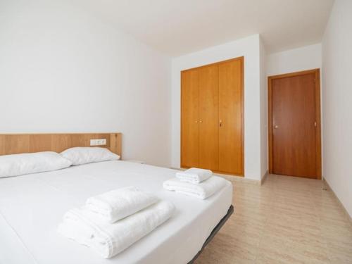 Fantástico y acogedor apartamento en Sant Feliu في سان فيليو دي غيكسولس: غرفة نوم بسرير ابيض عليها مناشف