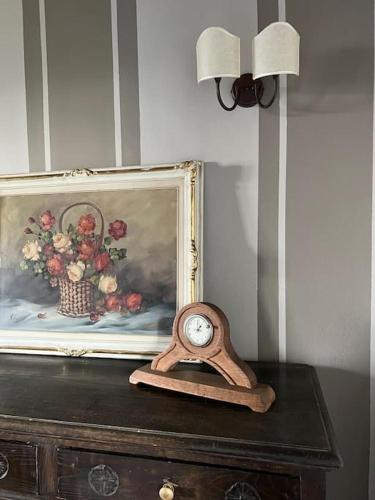 a clock sitting on top of a table with a picture at Peaceful Luxury Farmhouse - Stunning Alps Views in Saluzzo