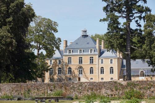 a large house behind a stone wall with a bench at DOMAINE LE MEZO in Ploeren