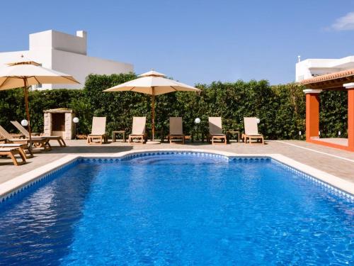 a swimming pool with lounge chairs and umbrellas at Villa KM2 lovely villa located just outside of Sa Carroca a 5 minute drive from Playa den Bossa in Sant Josep de Sa Talaia