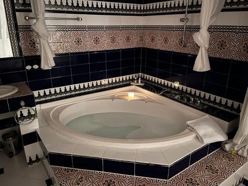 uma banheira na casa de banho com azulejos pretos e brancos em Hacienda Encanto del Rio em Es Figueral Beach