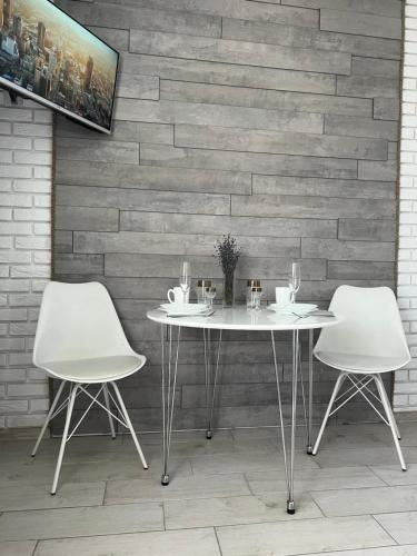 deux tables blanches et deux chaises devant un mur de briques dans l'établissement Квартира в центре, новострой, à Tchernihiv