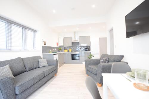 a living room with two couches and a kitchen at Stylish City Centre Apartments in Lincolnshire