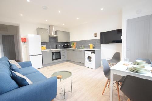 a living room with a blue couch and a kitchen at Stylish City Centre Apartments in Lincolnshire