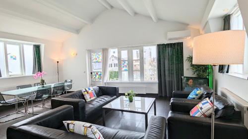 a living room with couches and a table and windows at The Hotel Apartments in the Center of Amsterdam in Amsterdam