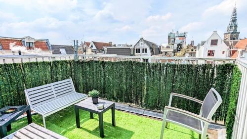 a patio with a bench and two chairs on a balcony at The Amsterdam Hotel Apartment in the Center in Amsterdam