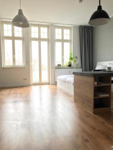 um amplo quarto branco com uma cama e piso em madeira em Charmantes Loft mit Balkon em Magdeburg