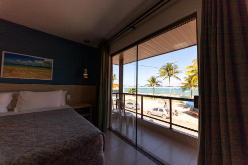 a bedroom with a bed and a view of the beach at Pousada Mariluz in Maragogi