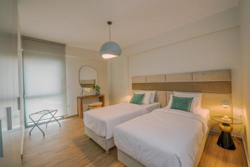 una camera d'albergo con due letti e uno specchio di HAMA Luxury Seaside Apartments a Korinthos